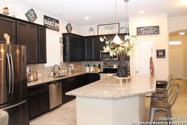 kitchen featuring pendant lighting, backsplash, a kitchen island, and stainless steel appliances