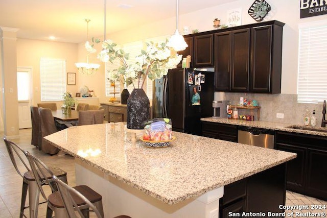 kitchen with tasteful backsplash, sink, pendant lighting, a center island, and fridge