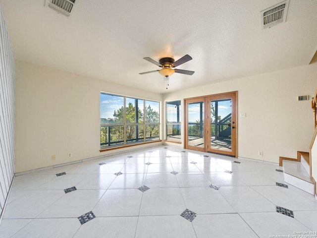 unfurnished room with ceiling fan, french doors, light tile patterned floors, and a textured ceiling