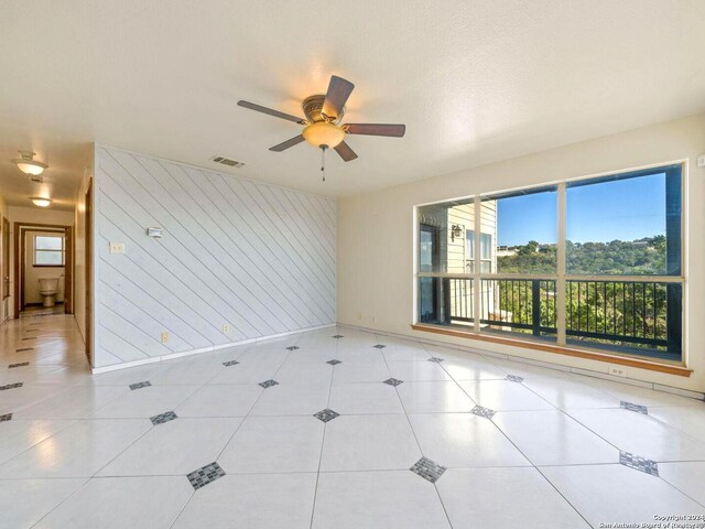 spare room with ceiling fan, light tile patterned floors, a textured ceiling, and wooden walls