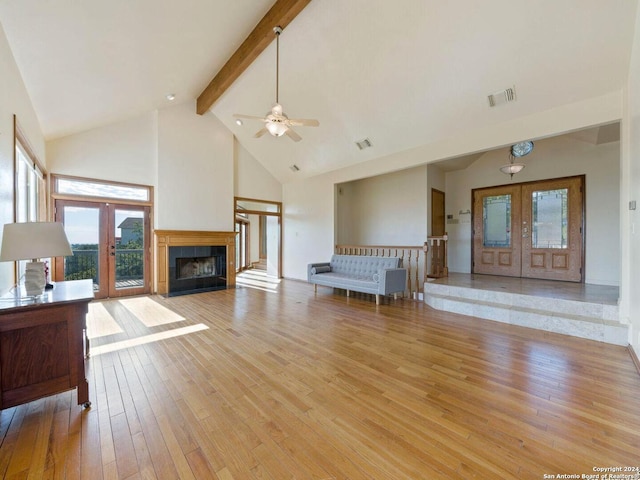 unfurnished living room featuring french doors, beamed ceiling, high vaulted ceiling, and light wood-type flooring