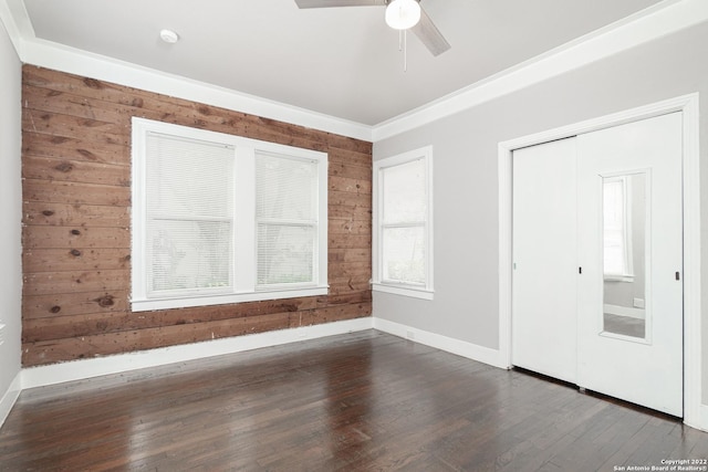 unfurnished room with wooden walls, dark hardwood / wood-style flooring, ceiling fan, and crown molding