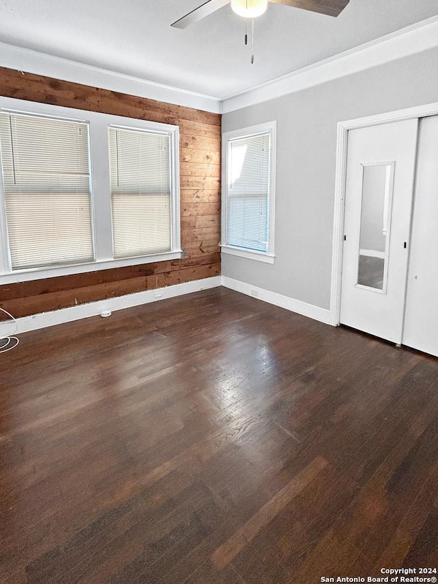 spare room with dark hardwood / wood-style floors, ceiling fan, and wooden walls