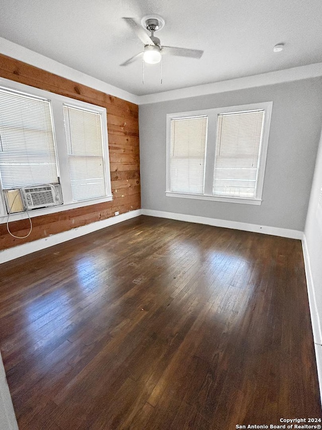 unfurnished room featuring ceiling fan, wood walls, dark hardwood / wood-style flooring, and cooling unit