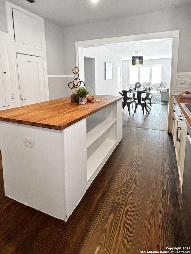 kitchen featuring butcher block countertops, white cabinetry, hanging light fixtures, and dark hardwood / wood-style floors