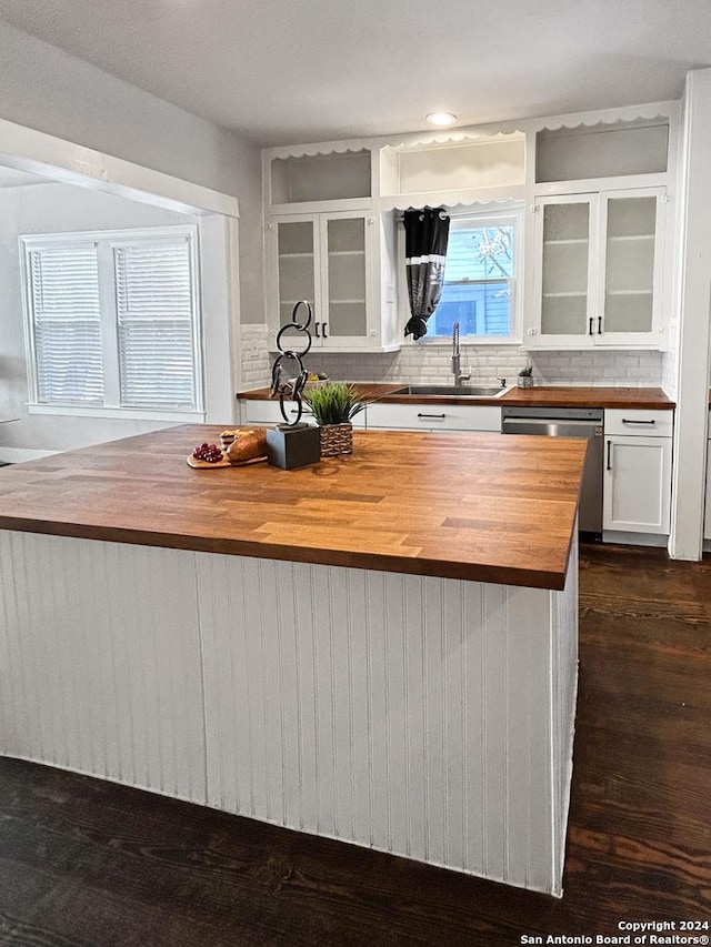939 Avant Ave, San Antonio, TX 78210 - kitchen with butcher block countertops, stainless steel dishwasher, white cabinetry, decorative backsplash, and glass insert cabinets