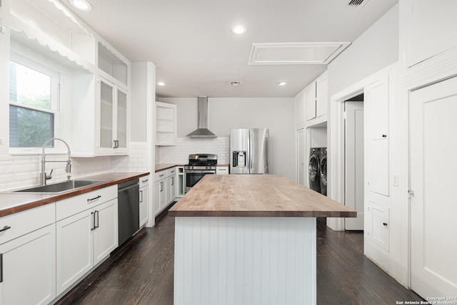 kitchen with white cabinets, appliances with stainless steel finishes, wood counters, and wall chimney range hood