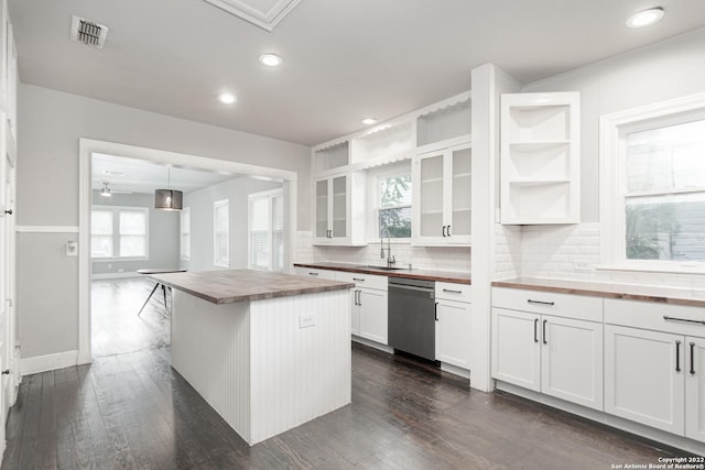 kitchen featuring white cabinetry, wood counters, stainless steel dishwasher, pendant lighting, and a kitchen island