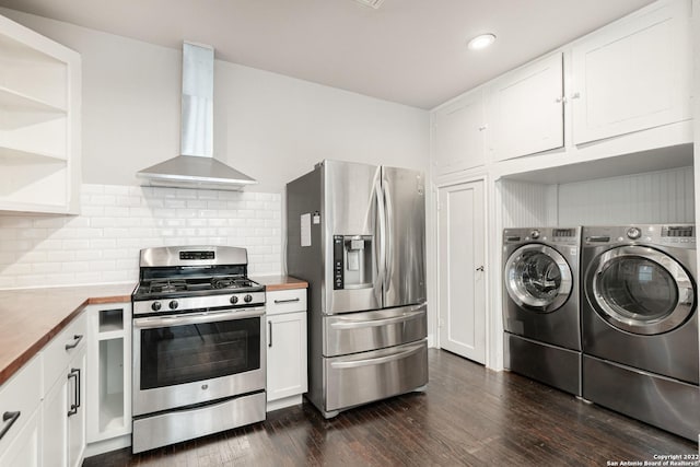 kitchen featuring wall chimney exhaust hood, stainless steel appliances, washing machine and dryer, wooden counters, and white cabinets