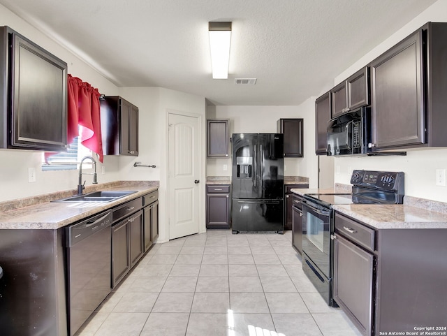 kitchen featuring a textured ceiling, dark brown cabinetry, sink, black appliances, and light tile patterned floors