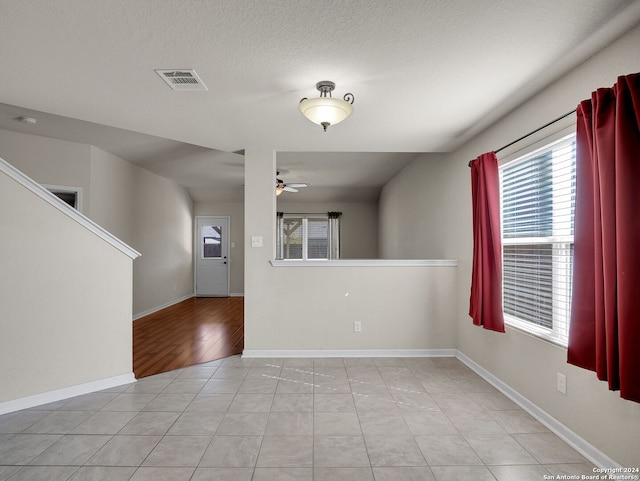 spare room with a textured ceiling, light hardwood / wood-style floors, and ceiling fan