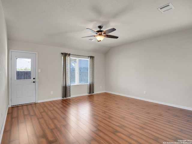 interior space featuring a textured ceiling, vaulted ceiling, ceiling fan, and dark wood-type flooring