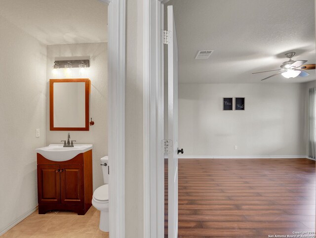 bathroom with vanity, ceiling fan, toilet, a textured ceiling, and wood-type flooring