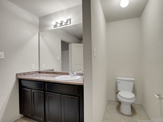 bathroom featuring tile patterned floors, vanity, a textured ceiling, and toilet