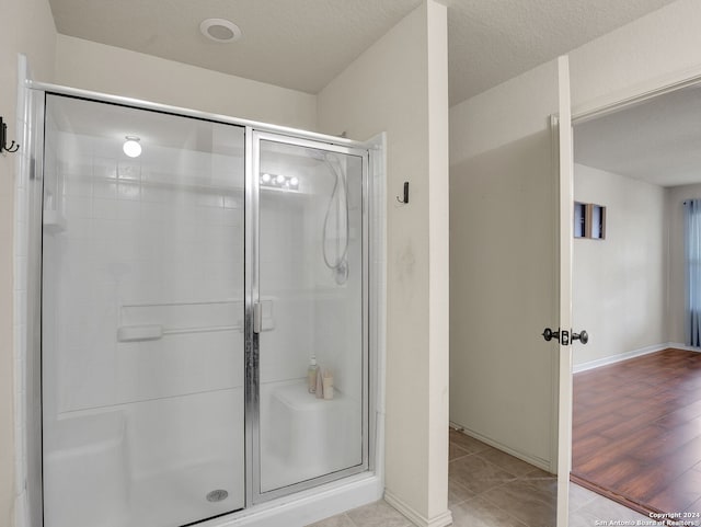 bathroom with hardwood / wood-style floors, a textured ceiling, and walk in shower