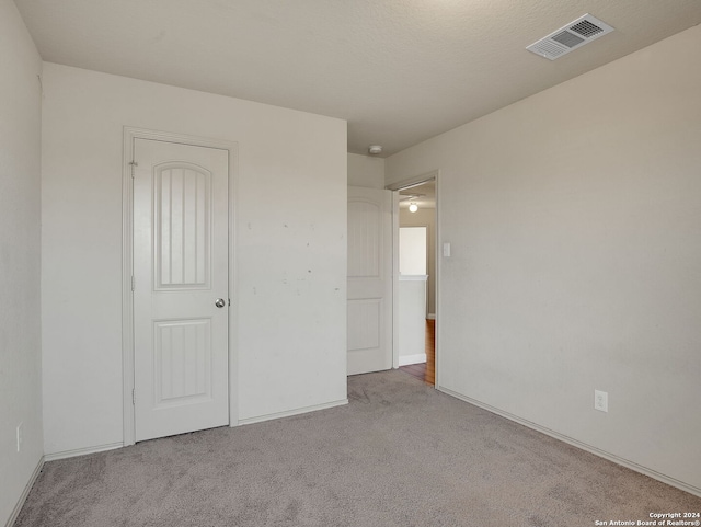 unfurnished bedroom with a textured ceiling and light colored carpet