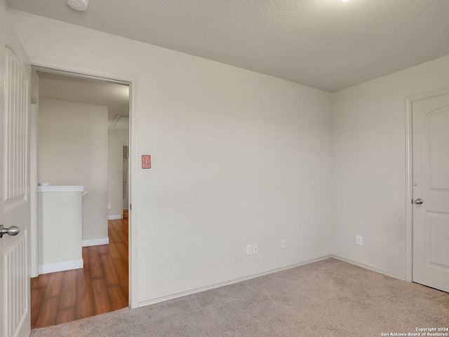 empty room with a textured ceiling and dark colored carpet