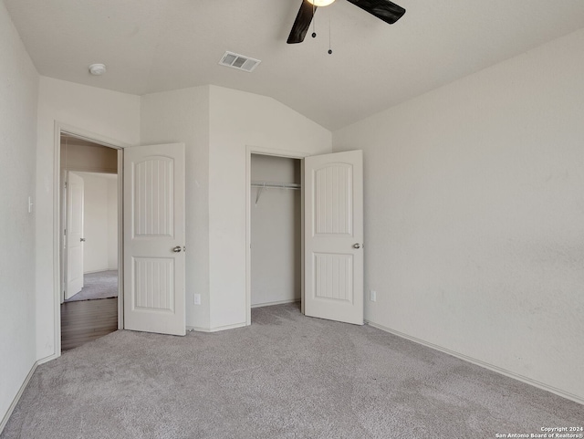 unfurnished bedroom with a closet, light colored carpet, vaulted ceiling, and ceiling fan