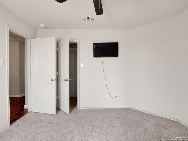 unfurnished bedroom featuring light carpet, a closet, and ceiling fan