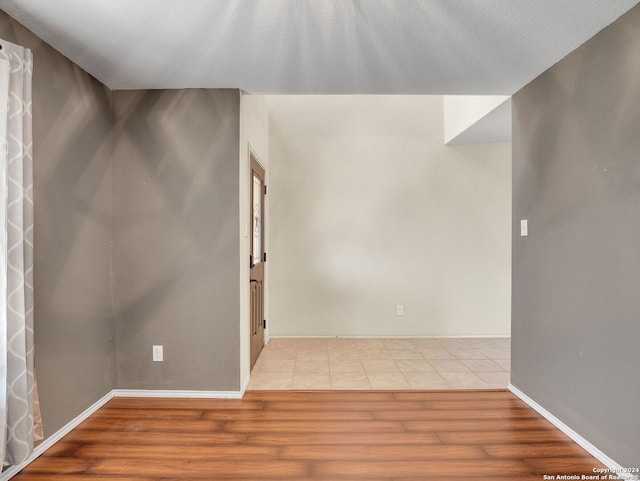 spare room with light wood-type flooring and a textured ceiling