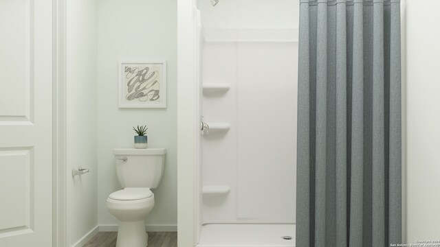 bathroom with toilet, wood-type flooring, and walk in shower