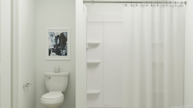 bathroom with a shower with shower curtain and toilet