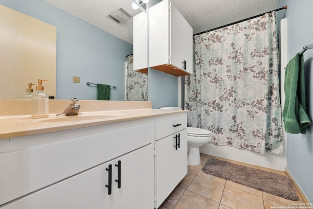 bathroom featuring tile patterned flooring, vanity, a textured ceiling, and toilet