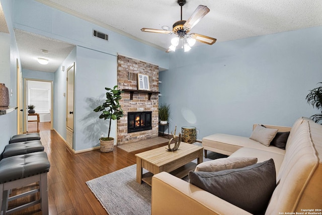 living room with hardwood / wood-style floors, a fireplace, ceiling fan, and a textured ceiling