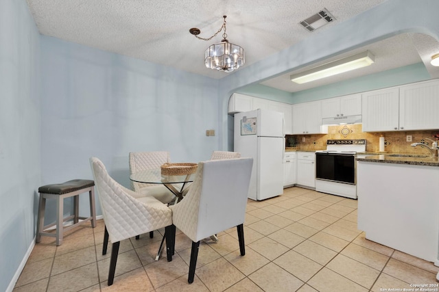 dining area with sink, light tile patterned floors, a textured ceiling, and an inviting chandelier