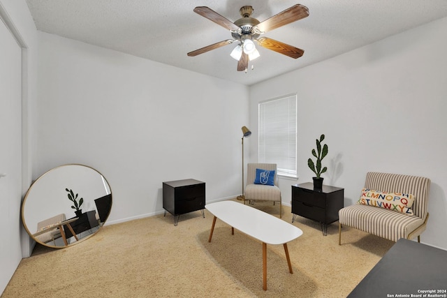 living area with a textured ceiling, carpet floors, and ceiling fan