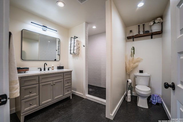 bathroom with toilet, tile patterned flooring, vanity, and tiled shower