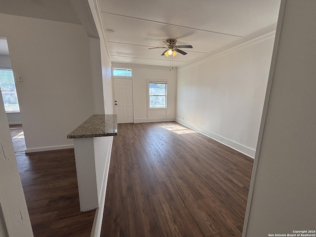 unfurnished living room featuring crown molding, ceiling fan, and dark wood-type flooring