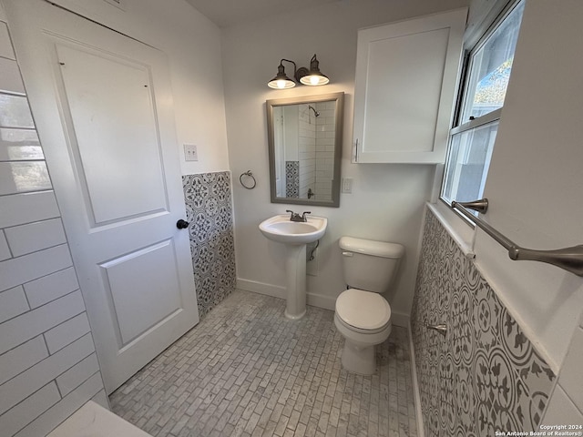 bathroom with toilet, tile walls, and sink