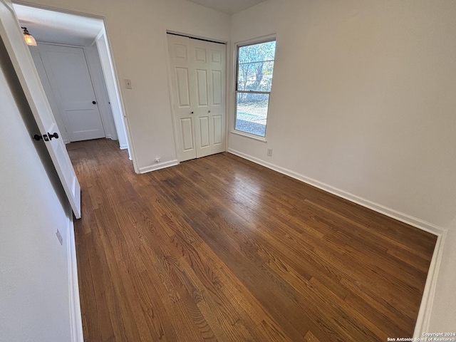 unfurnished bedroom with dark wood-type flooring and a closet