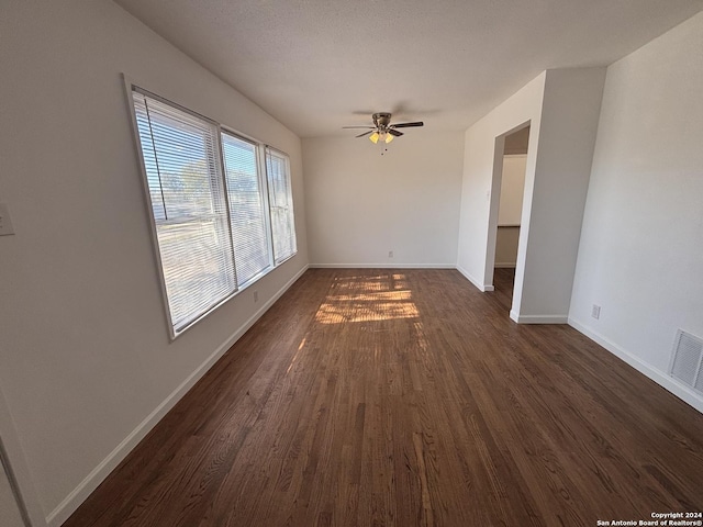 empty room featuring a textured ceiling, ceiling fan, and dark hardwood / wood-style floors