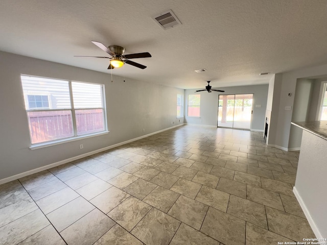 empty room featuring a textured ceiling, plenty of natural light, and ceiling fan