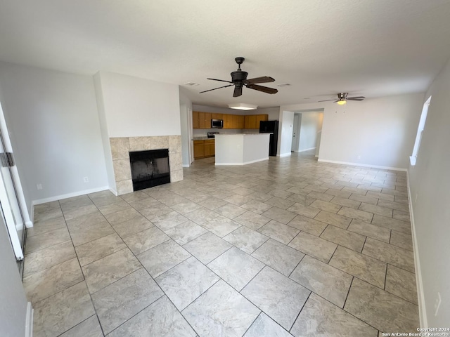 unfurnished living room featuring ceiling fan and a fireplace