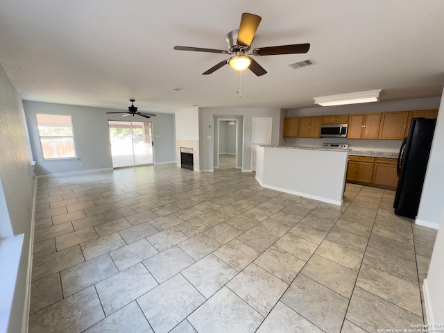 kitchen with a fireplace, black fridge, and ceiling fan