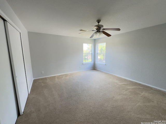 unfurnished bedroom featuring light carpet, a closet, and ceiling fan