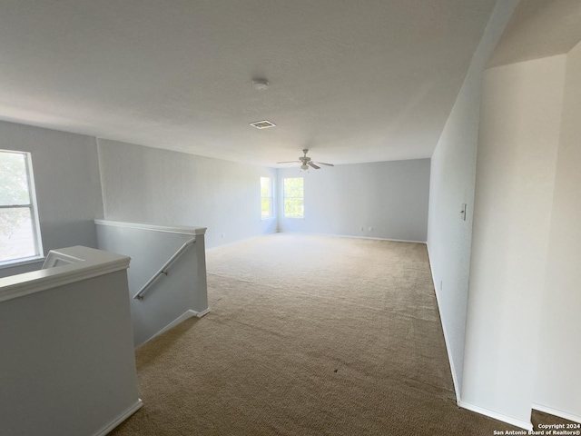 carpeted empty room featuring plenty of natural light and ceiling fan