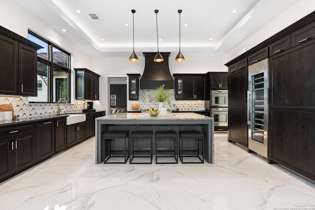 kitchen with backsplash, a kitchen island, decorative light fixtures, and premium range hood