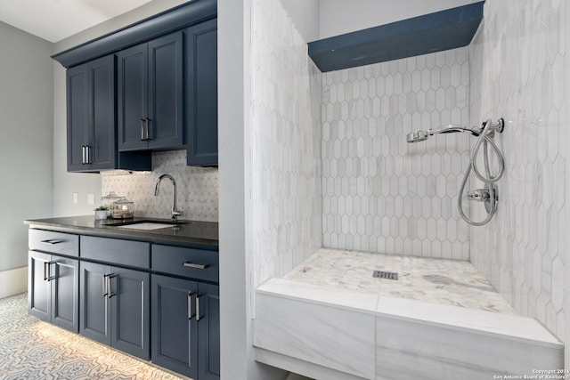 bathroom featuring tile patterned flooring, vanity, tiled shower, and tasteful backsplash