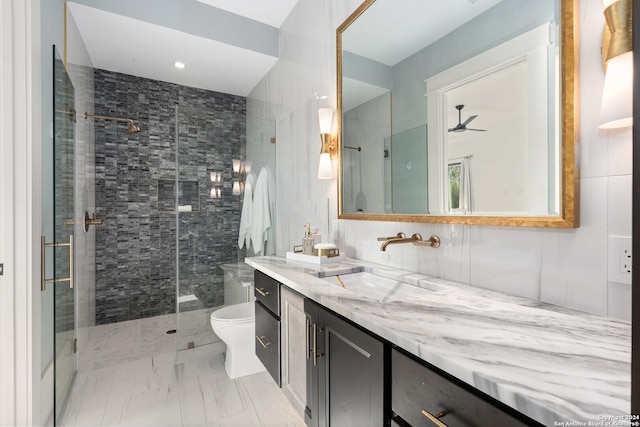 bathroom featuring an enclosed shower, vanity, ceiling fan, tile walls, and toilet