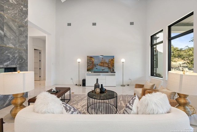 living room featuring tile patterned floors, a high end fireplace, and a towering ceiling