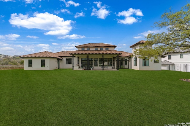 rear view of property featuring a tiled roof, a sunroom, stucco siding, and a yard