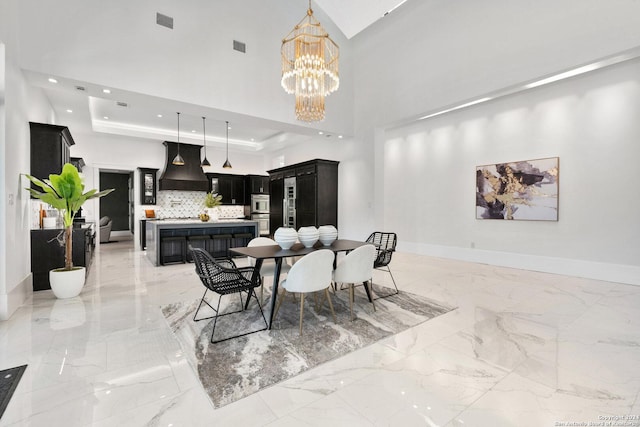 dining area featuring an inviting chandelier, a high ceiling, and a tray ceiling