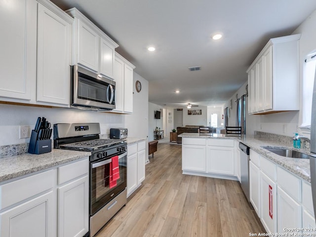 kitchen with white cabinets, sink, light hardwood / wood-style flooring, kitchen peninsula, and stainless steel appliances