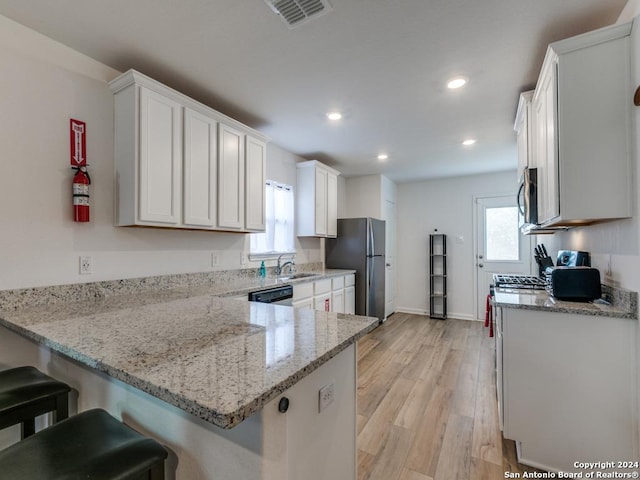 kitchen with kitchen peninsula, appliances with stainless steel finishes, light wood-type flooring, and white cabinetry