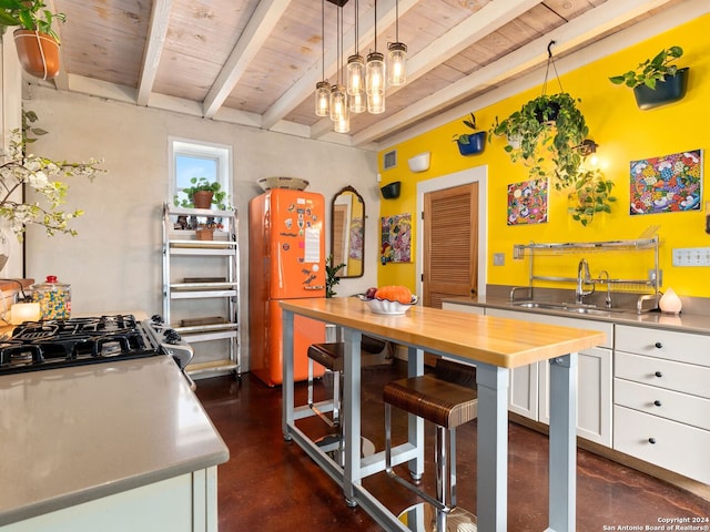 kitchen featuring white cabinetry, sink, stainless steel counters, white refrigerator, and decorative light fixtures