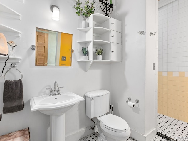 bathroom with tile patterned flooring, sink, toilet, and tiled shower